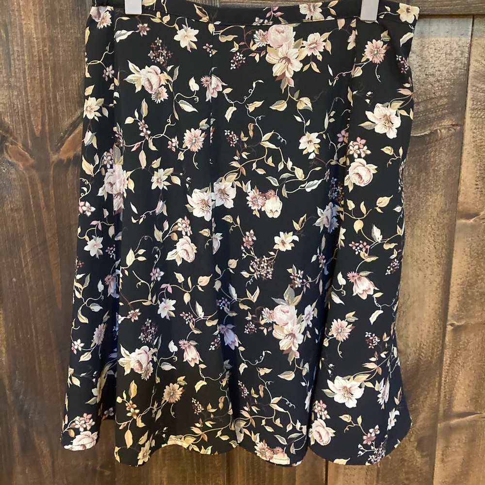 Knee length flows black skirt with flower print.